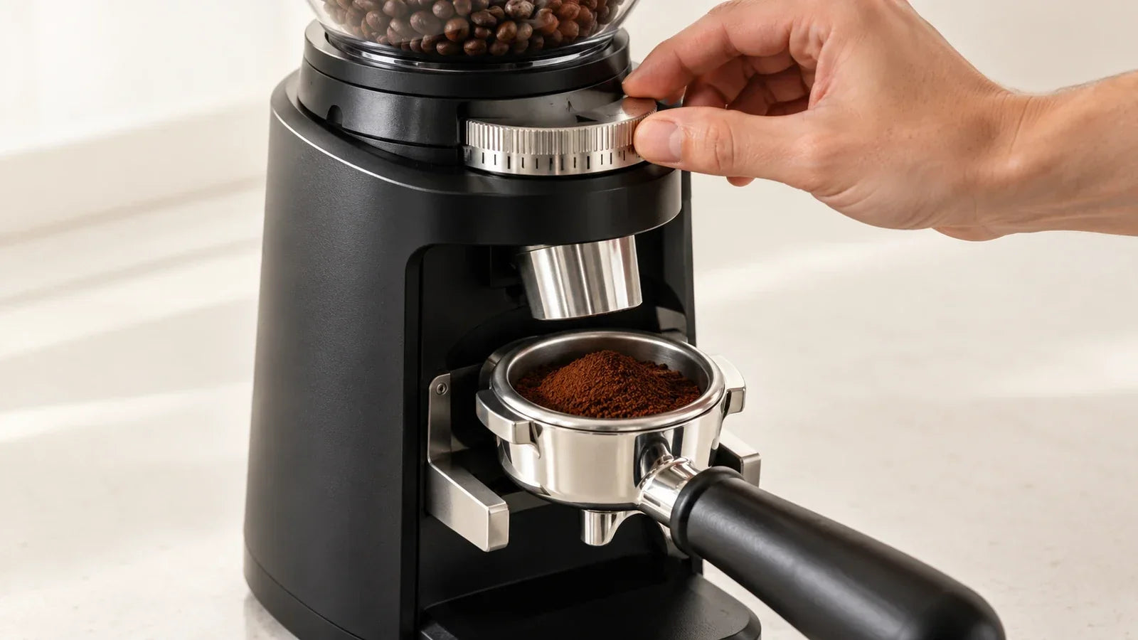 Adjusting an espresso grinder with fine coffee grounds in a portafilter.