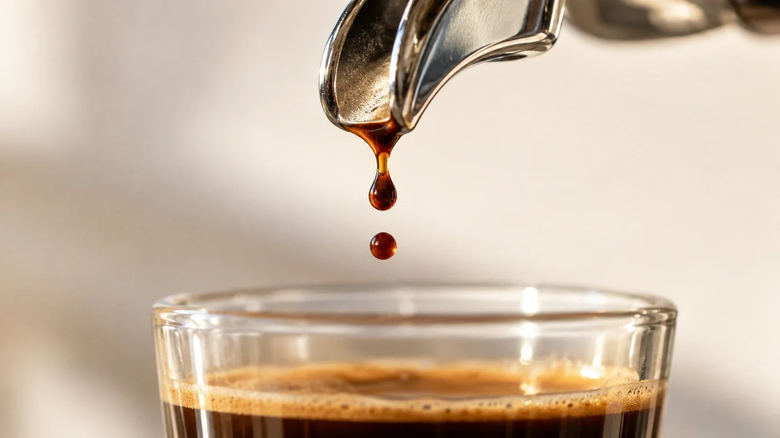 Close-up of separate espresso drops beneath a metal portafilter spout.